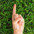 index finger pointing up with grass in background